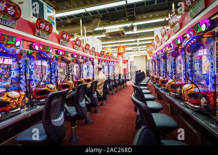 Tokyo, Japan - 12 Okt 2018: Eine ältere Japaner ist das Glücksspiel an einem Pachinko slot Maschine innerhalb eines Pachinko Salon in Tokio, Japan. Stockfoto