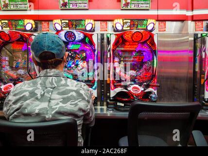 Tokyo, Japan - 12 Okt 2018: ein Japaner ist das Glücksspiel an einem Pachinko slot Maschine innerhalb eines Pachinko Salon in Tokio, Japan. Stockfoto