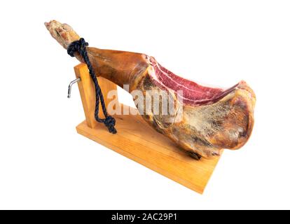 Jamon Serrano. Ein spanischer Schinken auf weißem Hintergrund. Traditioneller spanischer Jamon Serrano Bein isoliert. Trockenes Fleisch Schinken geheilt. Ganzes Bein. Jamon auf Papierstau Stockfoto