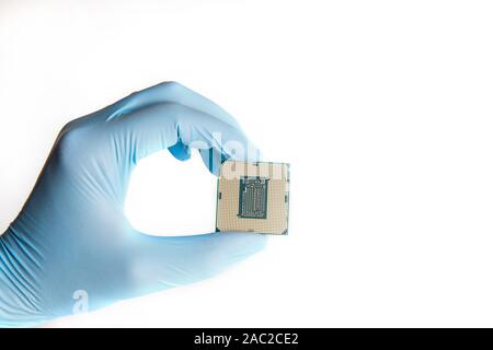 Hand in blau Handschuhe hält micro Prozessor CPU, bis zu schließen. Weißer Hintergrund. Stockfoto