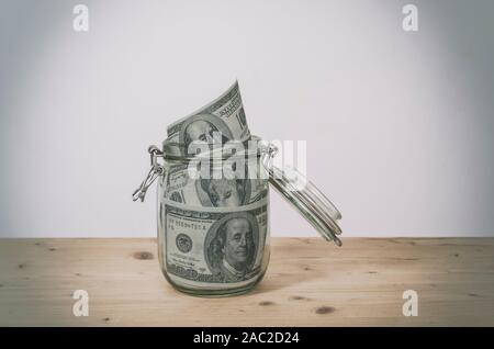 Dollarnoten in Glas Glas auf Holz- Tabelle. Geld sparen. Stockfoto