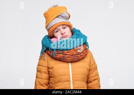 Junge Frau in mehrere Hüte und Schals nicht wie Winter an Kamera suchen Mit traurigen Ausdruck. Ich bin kalt. Studio shot Stockfoto