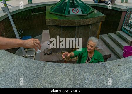 BORJOMI, Georgien - Juli 26, 2019: Nicht identifizierte Frau Wasser aus Borjomi Mineral Spring Stockfoto