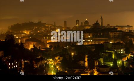 Bergamo, einem der schönsten Stadt in Italien. Tolle Landschaft der Nebel steigt aus den Ebenen und umfasst die Altstadt am Abend Stockfoto