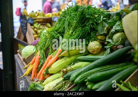 Frisches Gemüse angehäufte Höhe bereit für den Verkauf von Obst und Gemüse in Borough Market, London. Aus Fokus Kunden im Hintergrund. Stockfoto