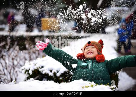 Ein junger chinesischer Junge spielt mit Schnee am Jingshan Park nach dem ersten Schneefall in diesem Winter in Peking, China, am 30. November, 2019. Beijing aufgezeichnet Stockfoto