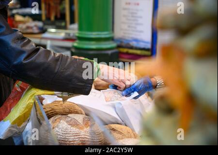 LONDON - September 27, 2019: Ein Kunde zahlt für Laibe Brot zu einem Brot in Borough Market, London. Stockfoto