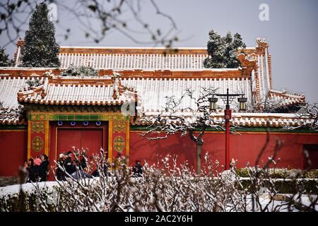 Menschen gehen vorbei an uralten Chinesischen Konstruktionen mit Schnee am Jingshan Park fallen nach dem ersten Schneefall in diesem Winter in Peking, China, am 3. November Stockfoto