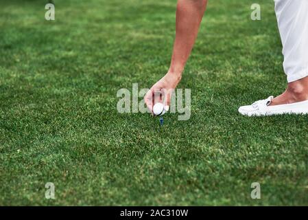 Weibliche hand Golf Ball auf dem Stift in den grünen Bereich Stockfoto