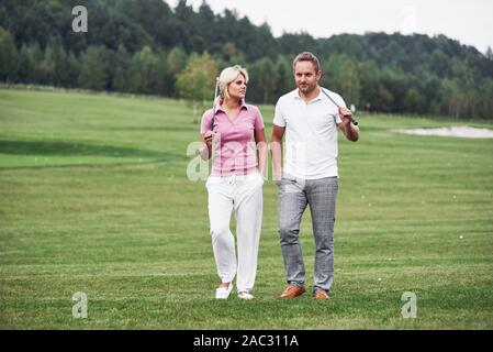 Paar Golfspieler mit Stöcken in den Händen Wandern auf dem Rasen Stockfoto