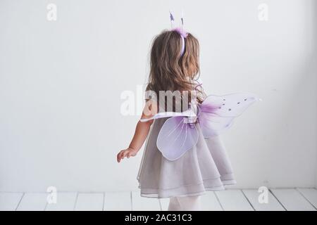 Zeigen Sie Ihre Flügel. Schönes kleines Mädchen in der Fee Kostüm stehen im Zimmer mit weißem Hintergrund Stockfoto