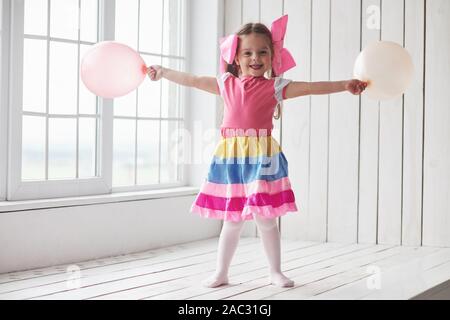 Luftballons heraus. Kind stand neben den Fenstern im weißen Raum und für ein Foto posieren Stockfoto