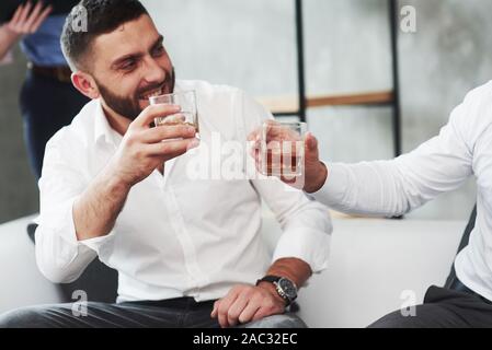Zwei Kollegen feiern gutes Angebot in Ihrem Geschäft durch das Trinken von Alkohol Stockfoto