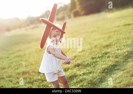 In die Luft starten. Gerne kleine Mädchen, die auf dem Feld mit dem roten Flugzeug in ihren Händen Stockfoto