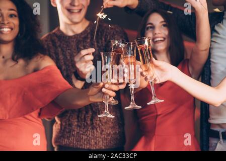 Champagner ist ein integraler Bestandteil. Multirassischen Freunde feiern das neue Jahr und bengalischen Lichtern und Gläser mit Getränk Stockfoto