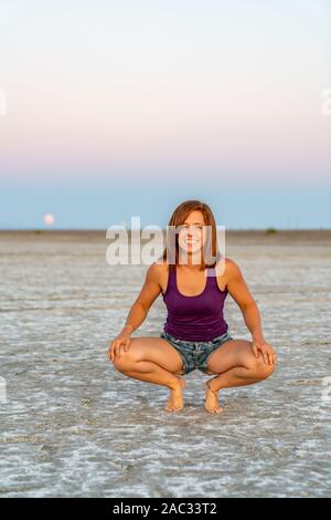 Schöne Frau macht Handstand während des Sonnenuntergangs in der Bonneville Salt Flats Stockfoto