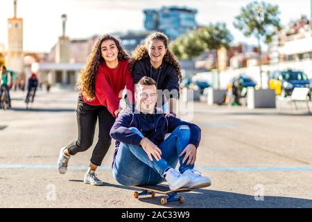 Drei Freunde spielen mit einem Skate Board Stockfoto