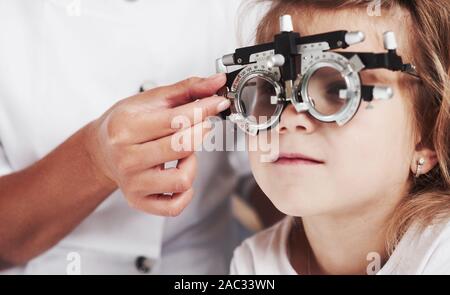 Nahaufnahme Foto. Arzt prüfen kleine Mädchen Anblick und das Tuning der phoroptor Stockfoto