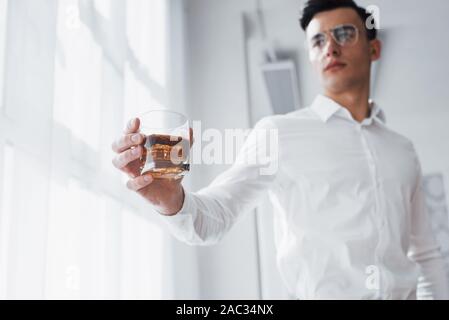 Nähe zu sehen. Wunderschöne Mann in Brillen stehen Innen- und Halten der Alkohol Stockfoto