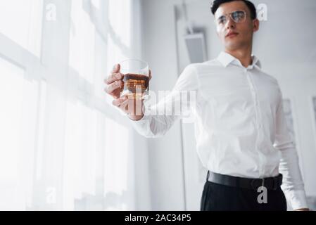 Konzentrieren Sie sich auf die goldene Whiskey. Wunderschöne Mann in Brillen stehen Innen- und Halten der Alkohol Stockfoto