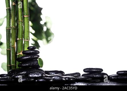 Grean Bambusblätter über schwarzen zen Steine Pyramide auf weißem Hintergrund Stockfoto