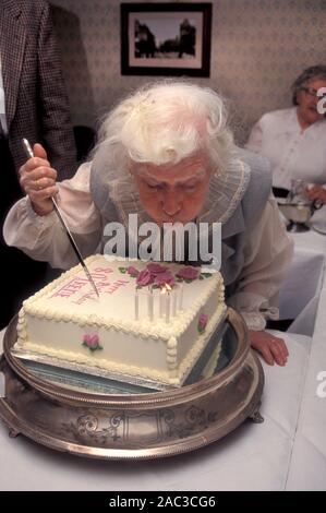 Lady ausblasen Kerzen auf Ihrem 80. Geburtstag Kuchen Stockfoto