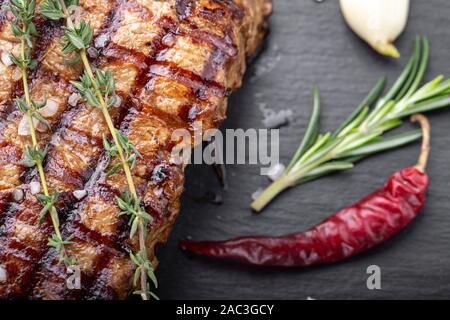 Holzkohle gegrilltes Steak mit Gewürzen, auf einem schwarzen Hintergrund. Grill Streifen auf Steak sichtbar Stockfoto
