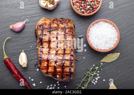 Holzkohle gegrilltes Steak mit Gewürzen, auf einem schwarzen Hintergrund. Grill Streifen auf Steak sichtbar Stockfoto