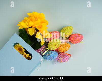 Ostereier und Blumen aus Party Papiertüte auf blauem Hintergrund. Ostereier in einem Papierbeutel. Osterhase. Kaninchen. Osterideen. Leerzeichen für Text. Stockfoto