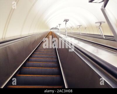 Abstieg in den Tunnel Stereo-Rolltreppe Treppe Licht von unten. Moderne Tunnel Rolltreppe elektronisches System bewegt Vintage-Stil, mechanisch Stockfoto