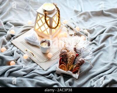 Weiße Schale mit Süßigkeiten, Orangen, Zitronen und Muttern auf einem grauen Holztisch. Helle, warme Lichter und Farben. Kaffee Pause. Citrus Süßigkeiten. Stockfoto