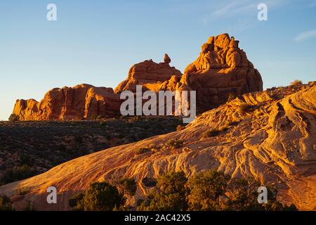 Das leuchtende Rot- und Orangetöne der Sandstein Felsformationen in der Arches National Park bei Sonnenuntergang. Stockfoto