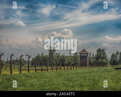 Oświęcim, Polen - Juni 05, 2019: elektrischen Zaun mit Stacheldraht und Wachturm im Konzentrationslager Auschwitz-Birkenau in Oświęcim, Polen. Eu Stockfoto