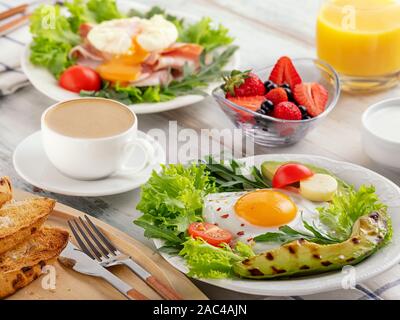 Gesundes Frühstück mit Spiegelei, Avocado, Tomaten, Toast und Kaffee und Orangensaft. Stockfoto