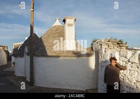Alberobello, Italien - 20. Oktober 2019. Die Frau auf der Straße mit Trulli (Trullo) Häuser am Abend. Stockfoto