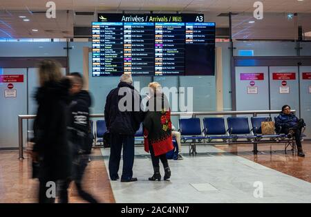 Nizza, Frankreich - 24.November 2019: Älteres Paar auf dem Flug Flughafen Zeitplan in Nizza Cote d'Azur Flughafen für den nächsten Flug verzögert Stockfoto