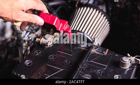 Hand des Techniker Service überprüfen Sie die Batteriespannung und schalten Sie die Batterie Schraube lose in einer Garage. Stockfoto