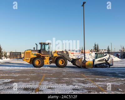 30 November 2019 - Calgary, Alberta, Kanada - Bau Geräte klar Schnee als stripmall Parkplatz genutzt Stockfoto