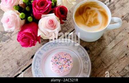 Tasse Kaffee, Kuchen und Blumen. Stockfoto