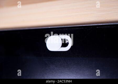 Nahaufnahme von einem weißen Kamera Datenschutz schieben Sie, Webcam Abdeckung für intelligente Geräte auf einem Holztisch Stockfoto