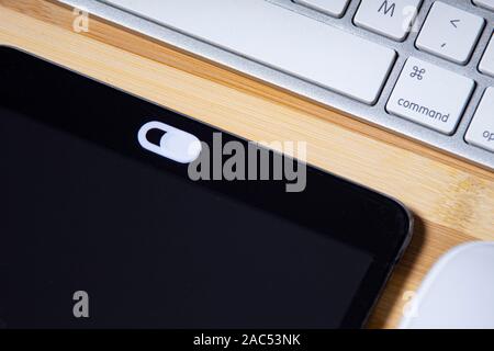 Datenschutz schieben Sie Kamera, Webcam Abdeckung für intelligente Geräte auf einem Holztisch mit Tastatur und Maus Stockfoto