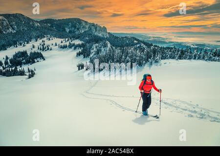 Gerne backpacker Frau auf frischen Pulverschnee, Skitouren auf den verschneiten Hügel. Backcountry skier Frau mit Rucksack und Mountain Equipment am Hang Stockfoto