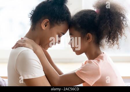 Afrikanische amerikanische Mutter und Tochter touch Stirn bewegender Moment genießen. Stockfoto