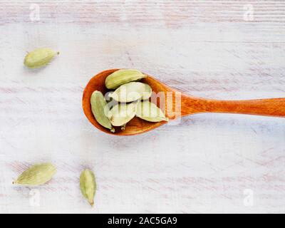 Gewürz Grüner Kardamom (Elettaria cardamomum) in einem Löffel auf einem weißen Holz- Hintergrund Stockfoto