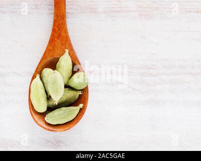 Gewürz Grüner Kardamom (Elettaria cardamomum) in einem Löffel auf einem weißen Holz- Hintergrund Stockfoto