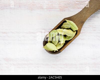 Gewürz Grüner Kardamom (Elettaria cardamomum) in einer Schaufel auf ein weißes Holz- Hintergrund Stockfoto