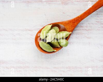 Gewürz Grüner Kardamom (Elettaria cardamomum) in einem Löffel auf einem weißen Holz- Hintergrund Stockfoto