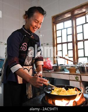 (191201) - SHILIN, Dez. 1, 2019 (Xinhua) - Li Xuezhi, 42, bereitet Essen für die Touristen in ihre Agritainment Restaurant in Danuohei Dorf Guishan Township in Shilin Yi Autonomen County, im Südwesten der chinesischen Provinz Yunnan, Nov. 28, 2019. Danuohei Dorf, mit einer Geschichte von über 600 Jahren, ist eine gut geschützte alte Dorf der Yi ethnischen Kultur. Anwohner gebauten Häuser und Straßen mit Steinen, die es einzigartig macht als "Dorf". Es ist von Bergen, Flüssen und der schönen Landschaft umgeben. Das Dorf hat nun 370 Haushalte mit einer Bevölkerung von 1000, von denen 99,8 Pe Stockfoto