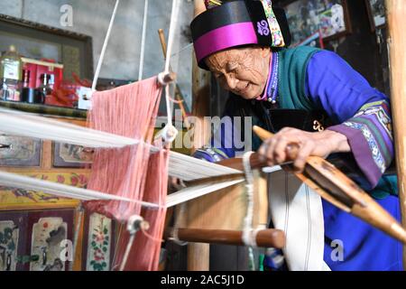 (191201) - SHILIN, Dez. 1, 2019 (Xinhua) - Bi Xiuzhen, 75, webt Leinen in Danuohei Dorf Guishan Township in Shilin Yi Autonomen County, im Südwesten der chinesischen Provinz Yunnan, Nov. 28, 2019. Danuohei Dorf, mit einer Geschichte von über 600 Jahren, ist eine gut geschützte alte Dorf der Yi ethnischen Kultur. Anwohner gebauten Häuser und Straßen mit Steinen, die es einzigartig macht als "Dorf". Es ist von Bergen, Flüssen und der schönen Landschaft umgeben. Das Dorf hat nun 370 Haushalte mit einer Bevölkerung von 1000, von denen 99,8 Prozent der Yi ethnischen Gruppe gehört. In rece Stockfoto