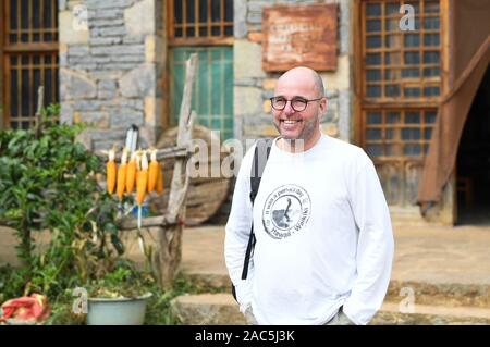 (191201) - SHILIN, Dez. 1, 2019 (Xinhua) - eine ausländische Touristen Danuohei Dorf Guishan Township in Shilin Yi Autonomen County, im Südwesten der chinesischen Provinz Yunnan, Nov. 28, 2019. Danuohei Dorf, mit einer Geschichte von über 600 Jahren, ist eine gut geschützte alte Dorf der Yi ethnischen Kultur. Anwohner gebauten Häuser und Straßen mit Steinen, die es einzigartig macht als "Dorf". Es ist von Bergen, Flüssen und der schönen Landschaft umgeben. Das Dorf hat nun 370 Haushalte mit einer Bevölkerung von 1000, von denen 99,8 Prozent der Yi ethnischen Gruppe gehört. In den letzten Jahr Stockfoto